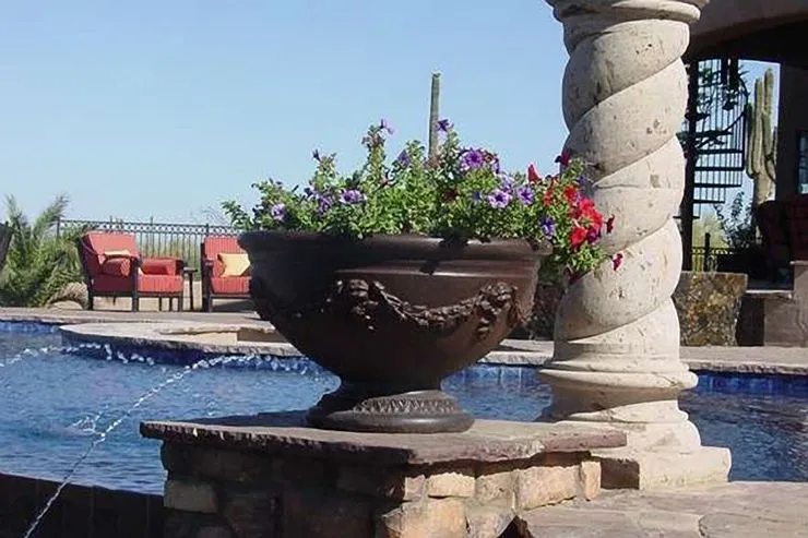 A large planter with flowers in it near the water.